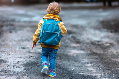 Young Child Walking Away With A Blue Backpack