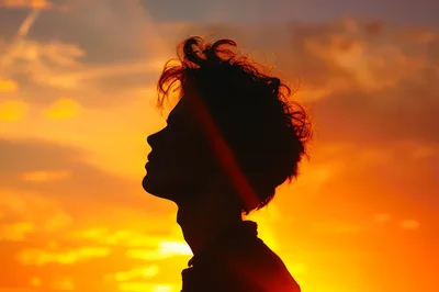 Silhouette Of A Young Man Against A Sunset Sky