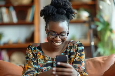 Young African Woman Smiling While Using Her Smartphone
