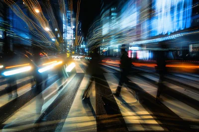 Motion Blur Pedestrians Crossing City Street At Night