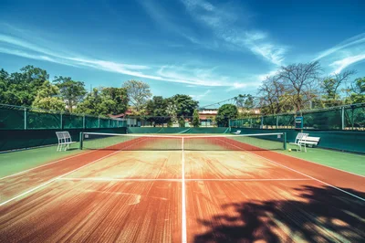 Empty Clay Tennis Court Under Bright Blue Sky