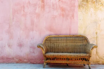 Wicker Sofa Against A Two Tone Pink And Beige Wall