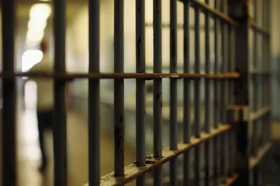 Blurred Silhouette Of A Prisoner Behind Metal Bars