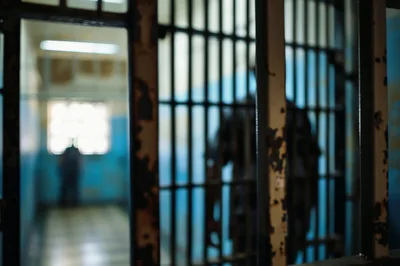 Silhouette Of A Prisoner Behind Metal Bars