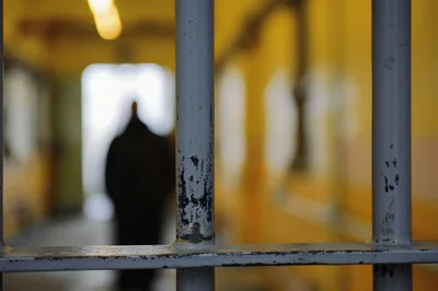Silhouette Of A Person Standing Behind Prison Bars