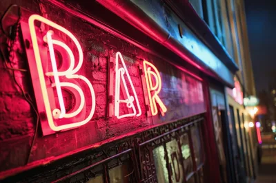 Neon Bar Sign Glowing On A Dark Brick Wall