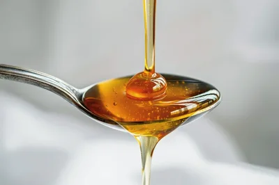 Golden Honey Pouring Onto A Silver Spoon