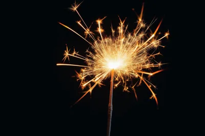 Bright Burning Sparkler Against A Solid Black Background