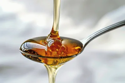 Golden Honey Pouring Onto A Silver Spoon