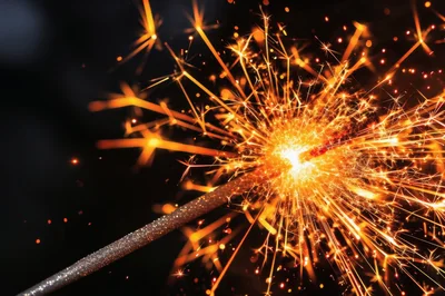 Bright Burning Sparkler Against Dark Background