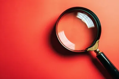 Magnifying Glass Resting On A Vibrant Red Background