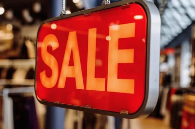 Illuminated Red Sale Sign Hanging In Clothing Store