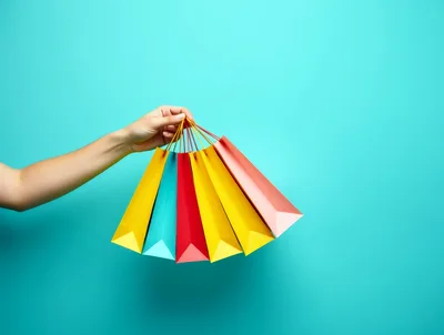 Hand Holding Colorful Shopping Bags Against Turquoise Background