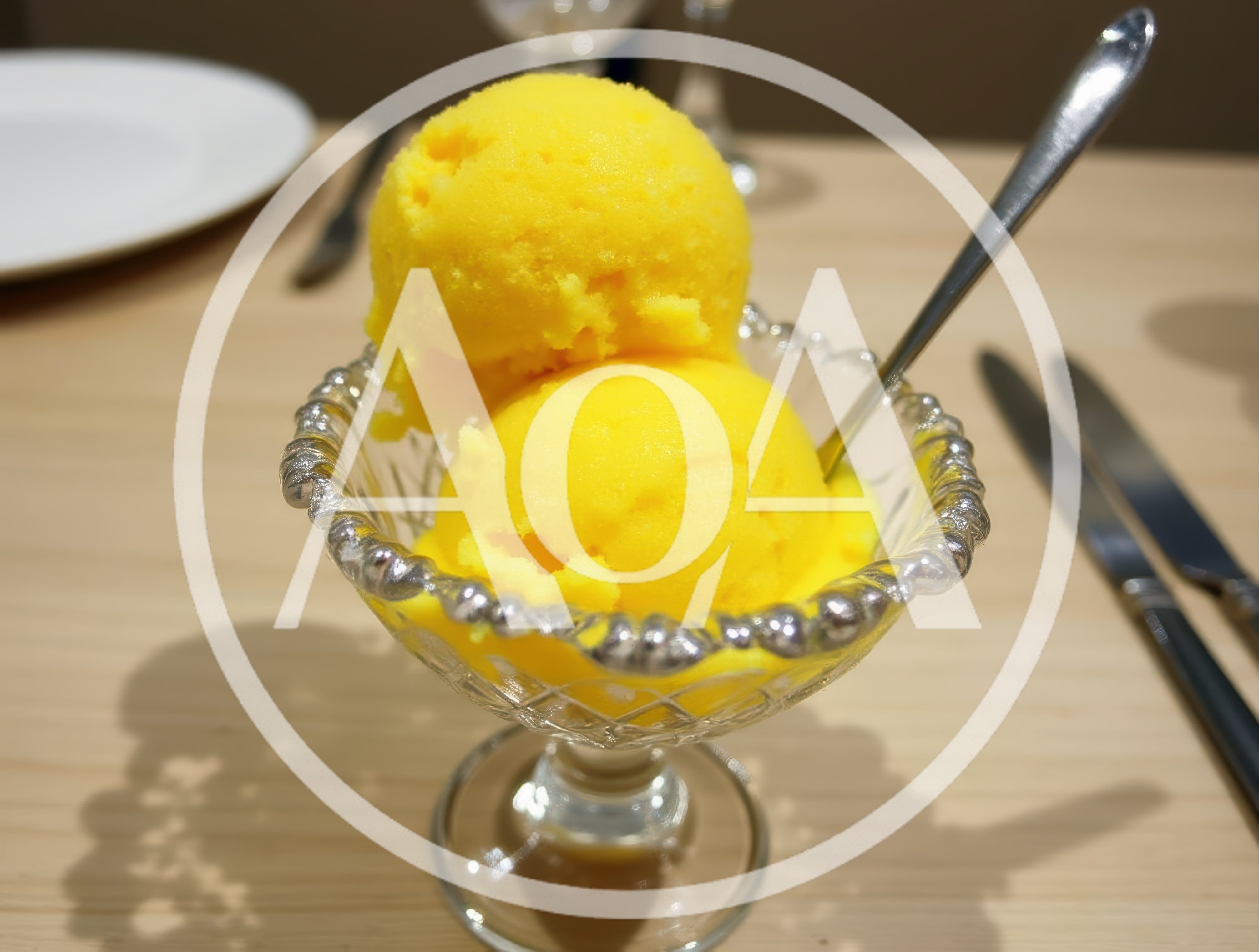 Two Scoops Of Bright Yellow Mango Sorbet In Crystal Bowl