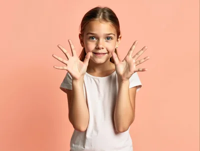 Young Girl Showing Ten Fingers Against Peach Background
