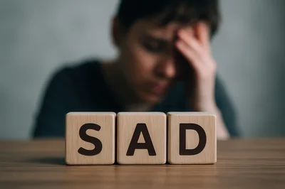 Person Feeling Sad With Wooden Blocks Spelling Sad