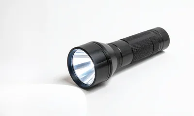Black Metal Flashlight Shining Light On White Surface