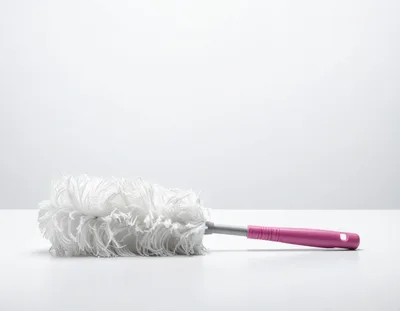 White Feather Duster With Pink Handle On White Surface