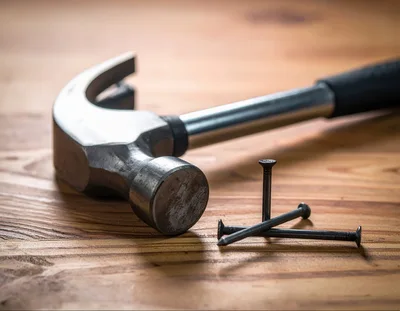 Claw Hammer And Three Nails On Wooden Surface