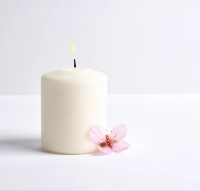 Lit White Pillar Candle With A Pink Cherry Blossom