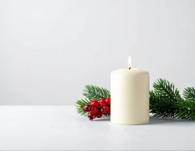 Lit White Pillar Candle With Christmas Greenery