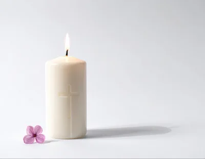 Lit White Candle With Cross And Lilac Flower