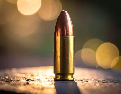 Single Brass Bullet Standing Upright On Wooden Surface