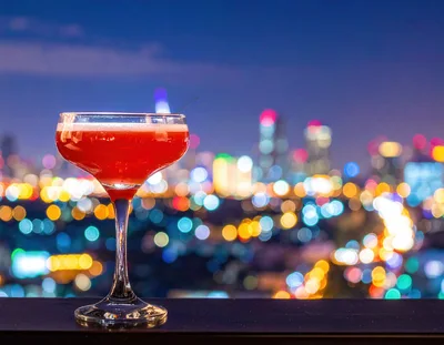 Red Cocktail Glass Against Blurred City Night Lights
