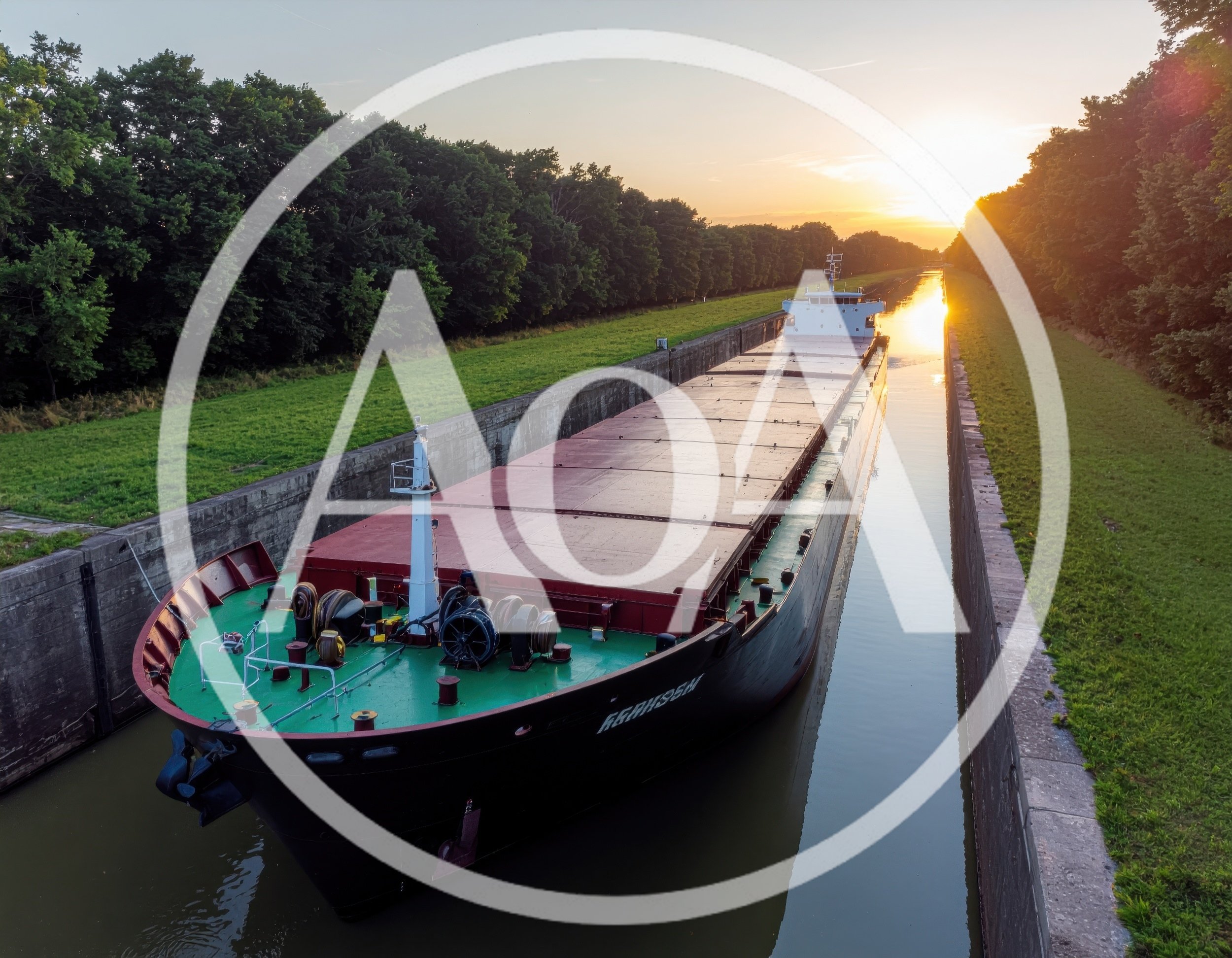 Cargo Ship Navigating Through A Narrow Canal At Sunset