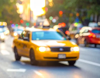 Yellow Taxi Cab Driving Through Busy City Street