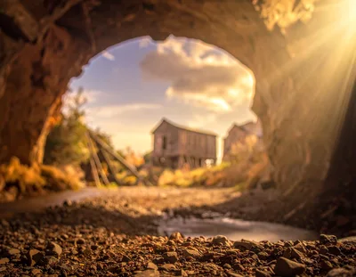 Old Wooden Barn Seen Through A Natural Stone Archway