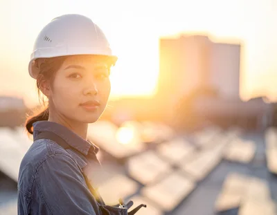 Female Engineer Inspecting Solar Panels At Sunset