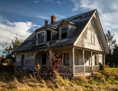 Abandoned Weathered Farmhouse In A Grassy Field