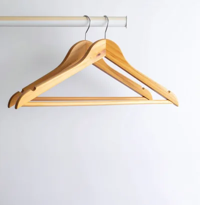 Two Wooden Clothes Hangers Hanging On A Rod
