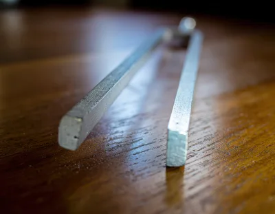 Metal Tuning Fork Resting On Wooden Table