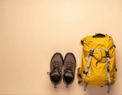 Hiking Backpack and Boots on Beige Background