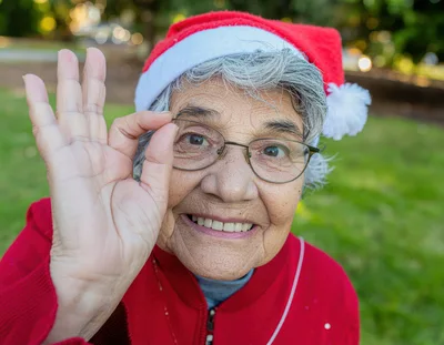 Senior Woman Wearing Santa Hat Making OK Gesture