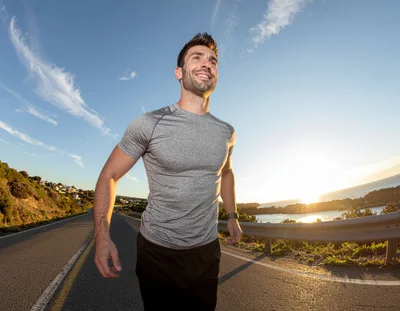 Athletic Man Running Along Coastal Road At Sunset