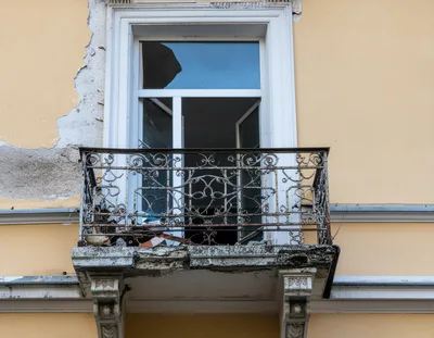 Dilapidated Balcony With Wrought Iron Railing On Old Building