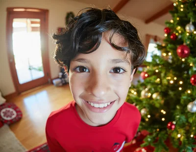 Young Boy Smiling Near Christmas Tree