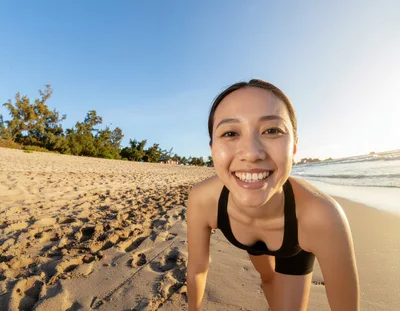 Young Woman Doing Pushups On A Sunny Beach