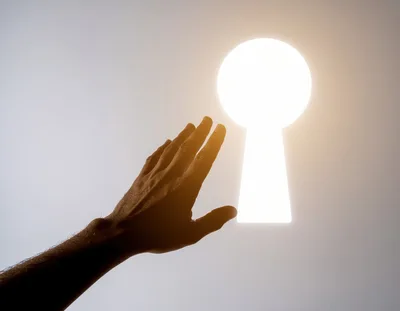 Human Hand Reaching Toward A Glowing Keyhole