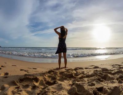 Woman Standing On Beach At Sunset
