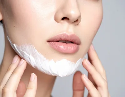 Woman Applying White Skincare Cream To Her Chin