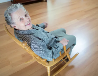 Senior Woman Smiling In A Wooden Rocking Chair