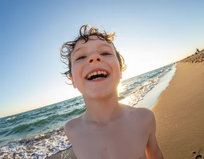 Happy Young Boy Smiling On Sunny Beach