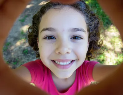Young Girl Looking Through A Circular Playground Tunnel