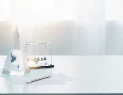Glass Prism and Newtons Cradle on Office Desk