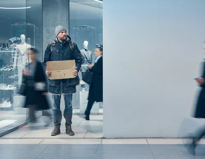 Homeless Man Holding Cardboard Sign In Modern Shopping Mall