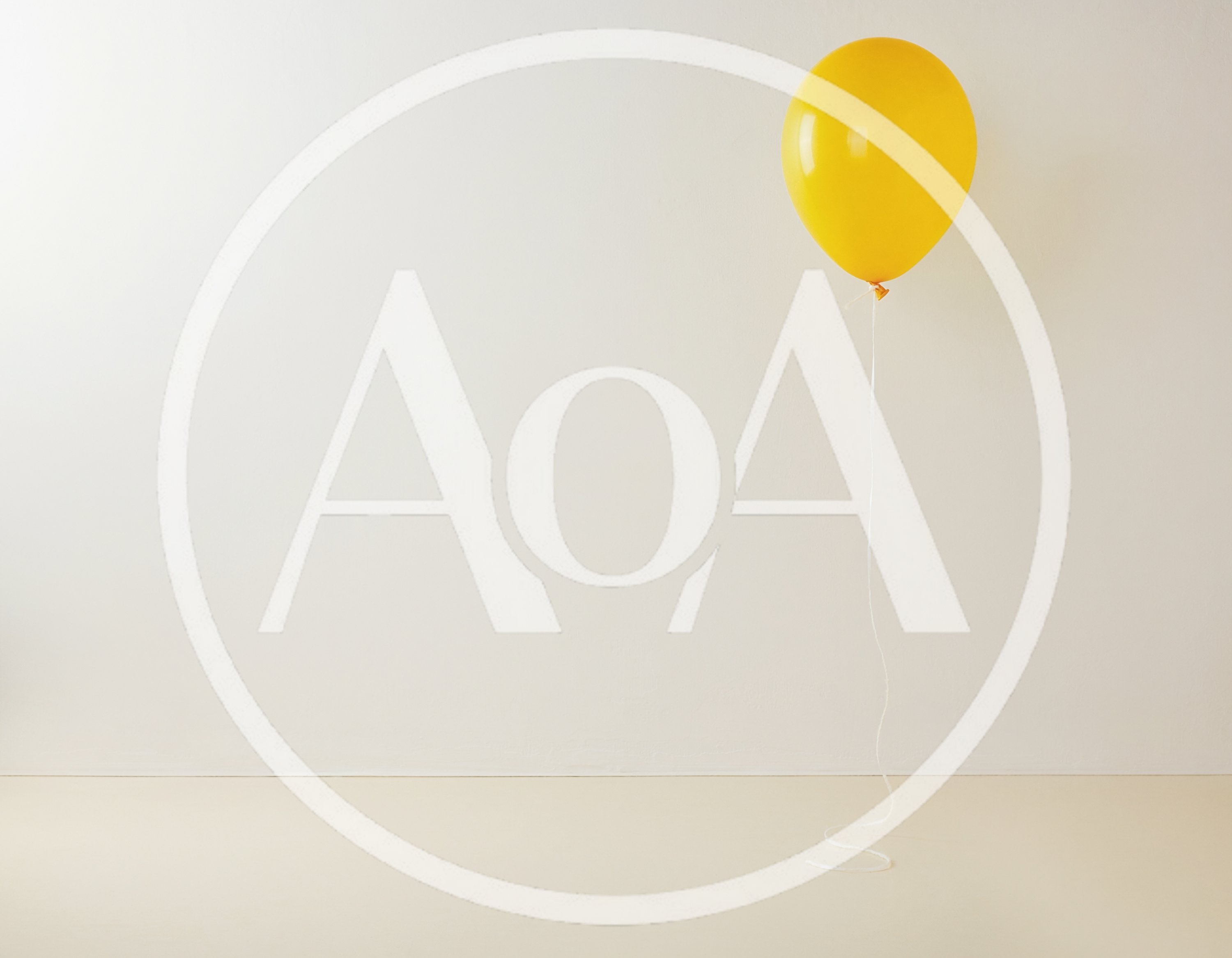 Single Yellow Balloon Floating Against A Plain Wall